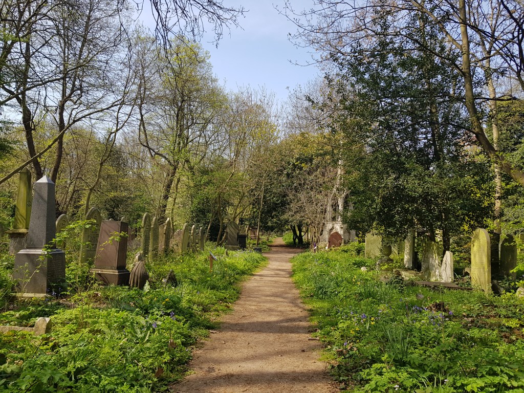 Photograph of a walking path with gravestones on both sides in Tower Hamlets Cemetery