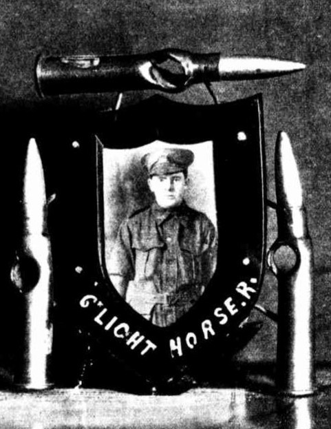 Newspaper photograph of a soldier and three bullet cases with holes in them